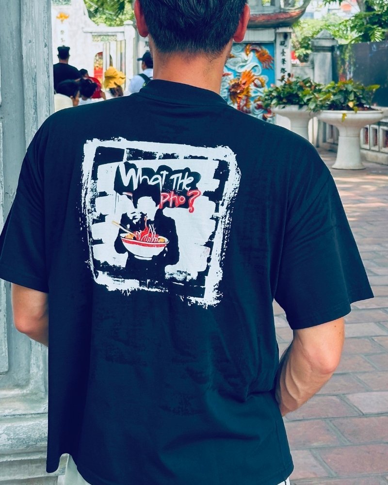 Person standing at a asian temple gate wearing a black Spicy Lotus shirt with graphic design.