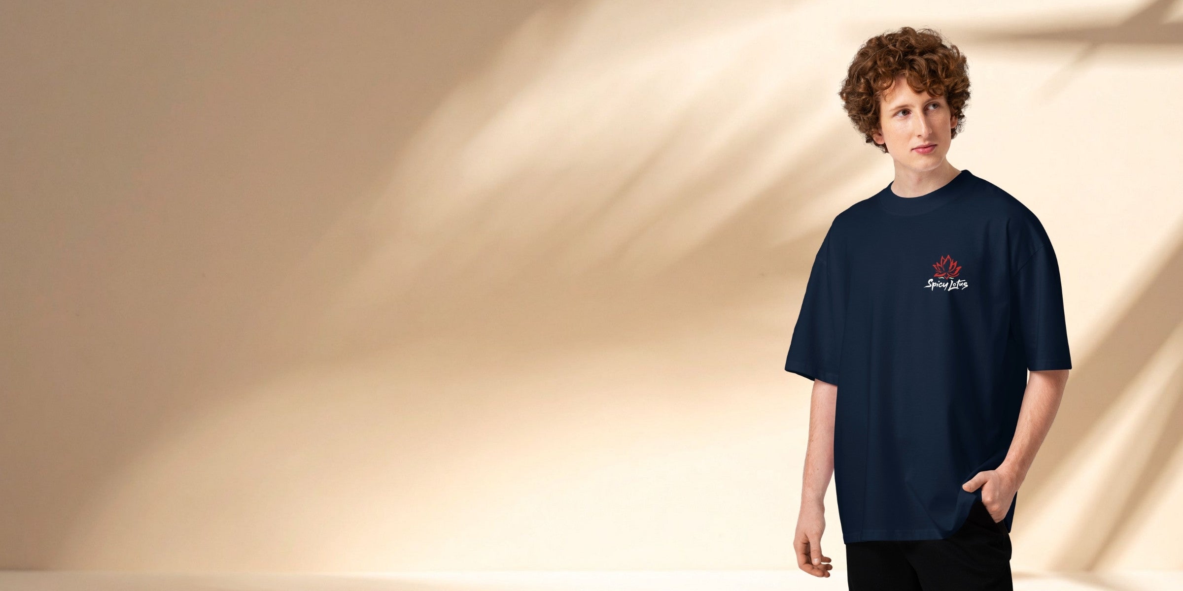 Man in oversized shirt standing in front of a tropical wall with palm leaf shadows in the background.