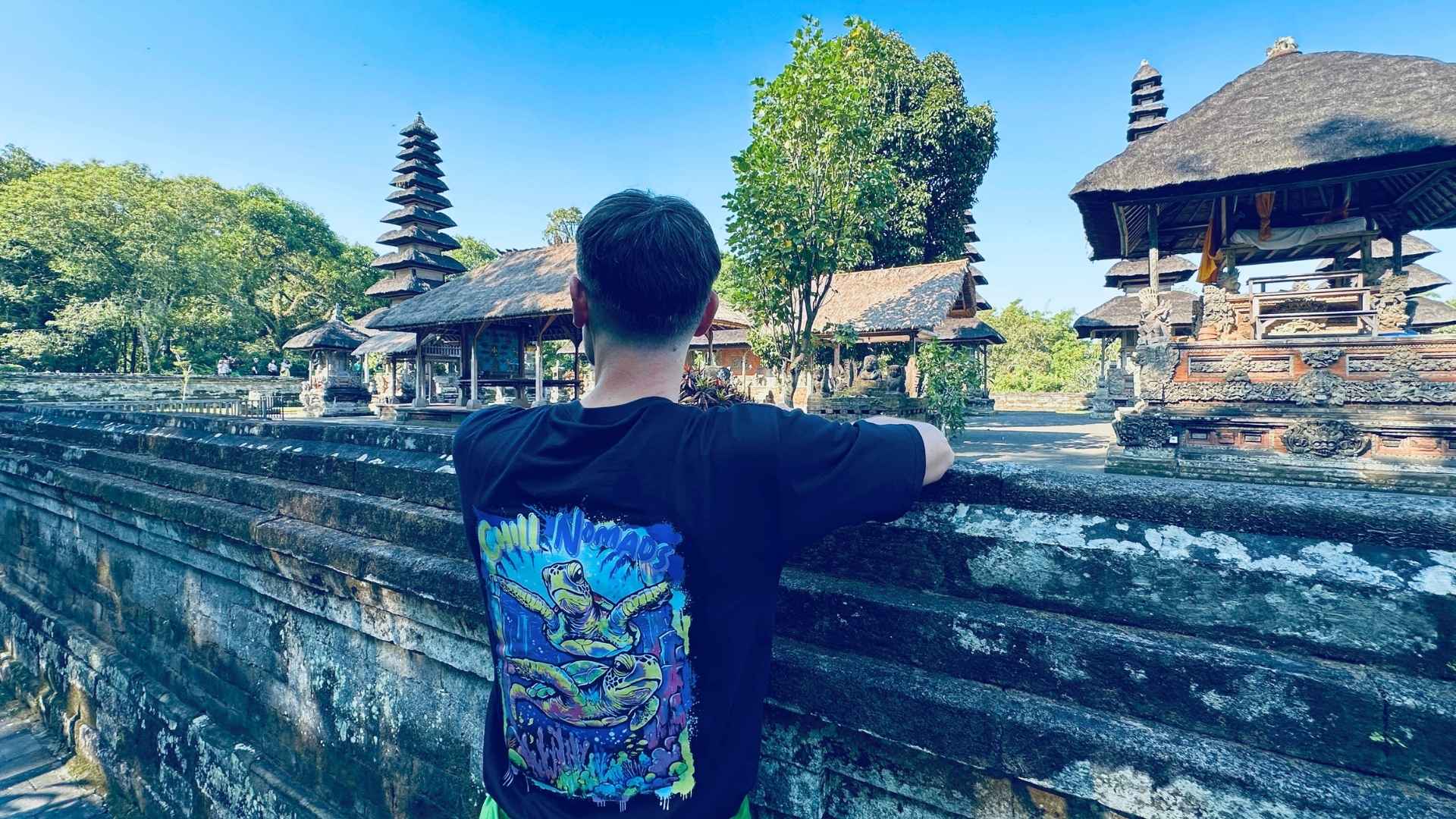 Person standing at a temple complex with traditional architecture and colorful t-shirt design.