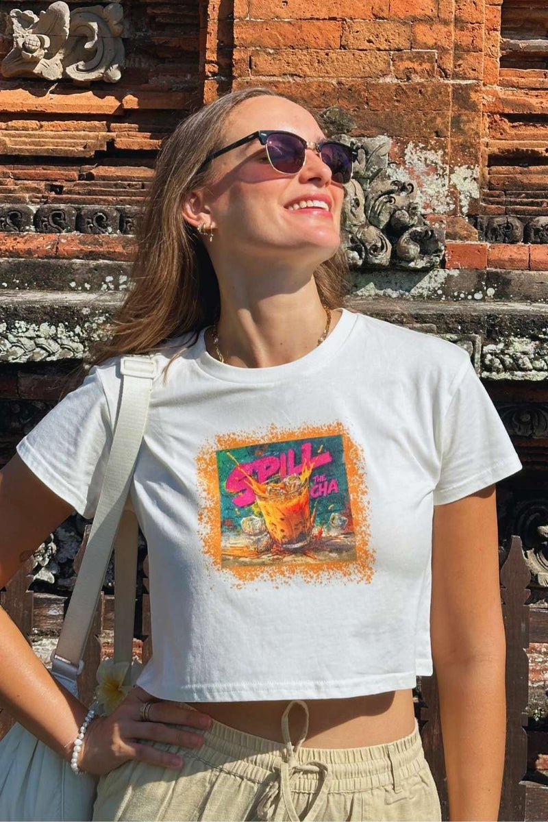 Woman wearing a white crop top with a colorful thai tea graphic design.