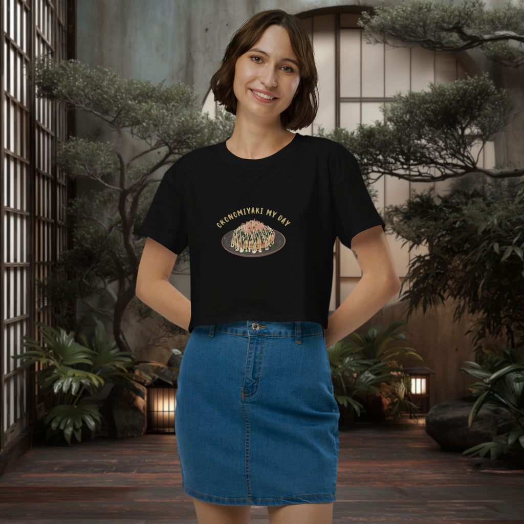 Woman wearing a black crop top with a graphic design in an indoor setting with plants.