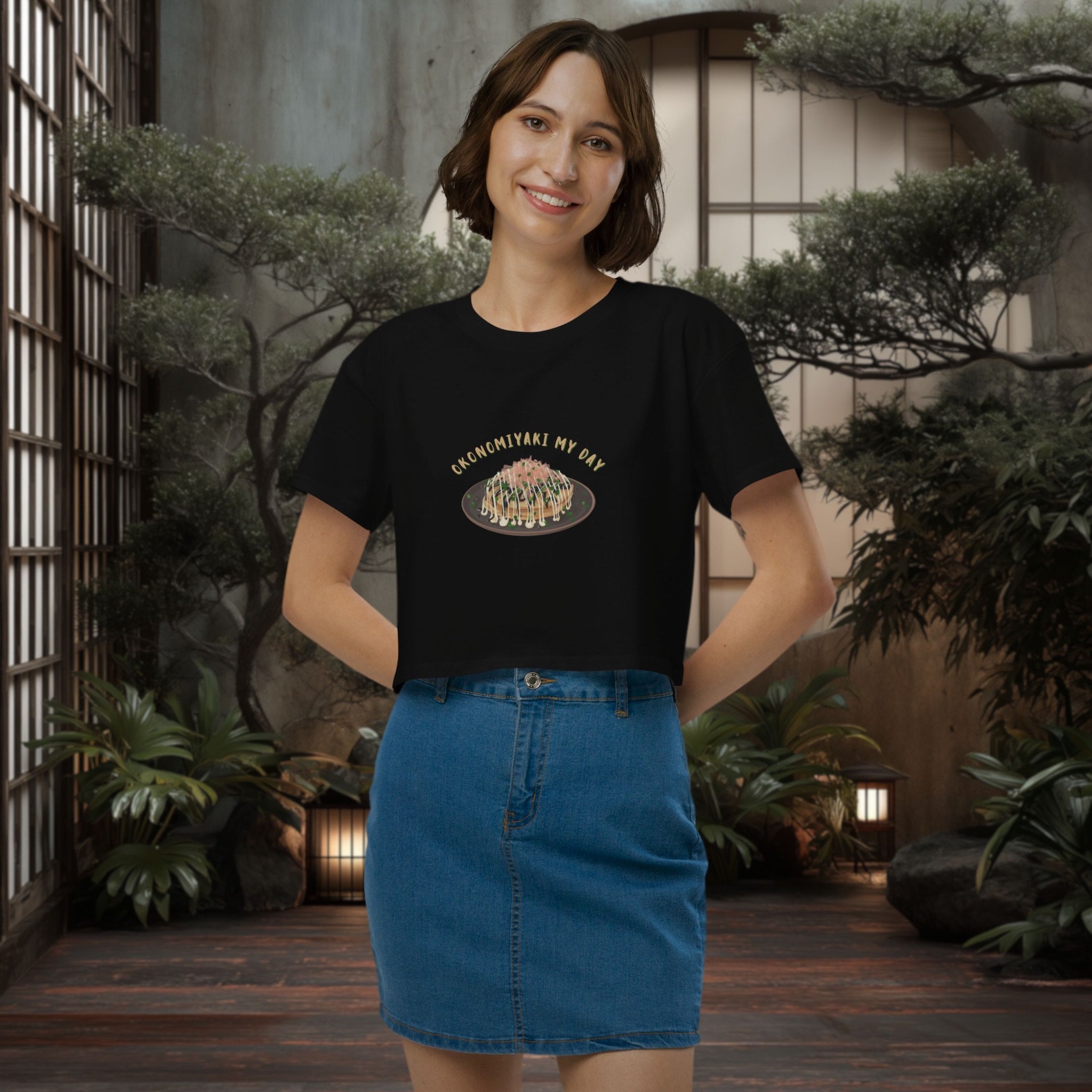 Woman wearing a black crop top with a graphic design in an indoor setting with plants.