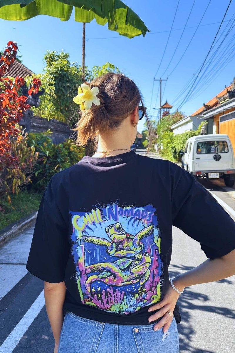 Person wearing a black t-shirt with colorful Spicy Lotus turtle graphic design on a street.