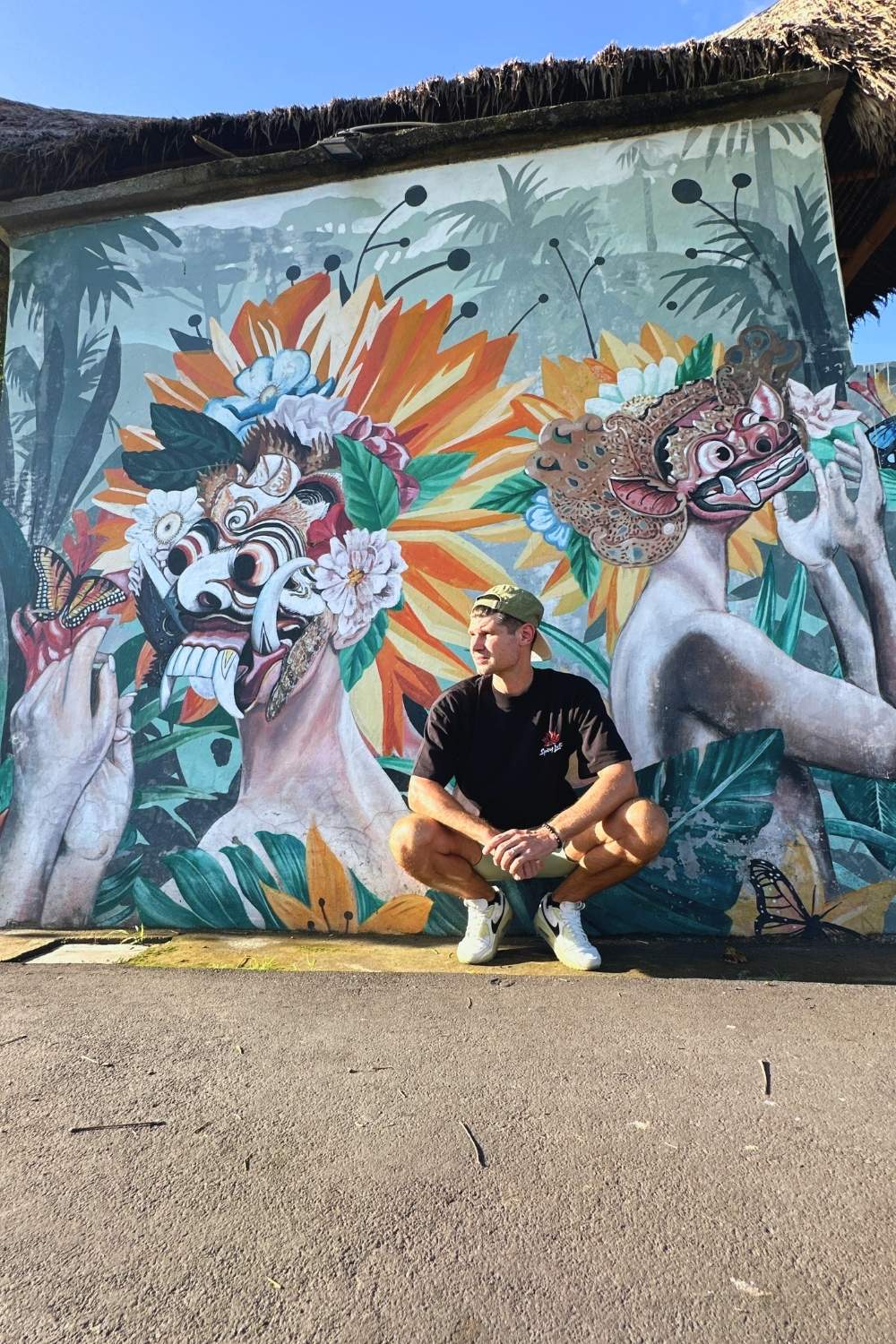 Male model posing in front of a colorful mural with abstract balinese designs.