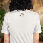 Person wearing a white t-shirt with 'Spicy Lotus' logo on the back, standing against a rustic wall.