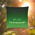 Green pillow with text 'Call me later, I'm in the jungle' on a blurred natural background