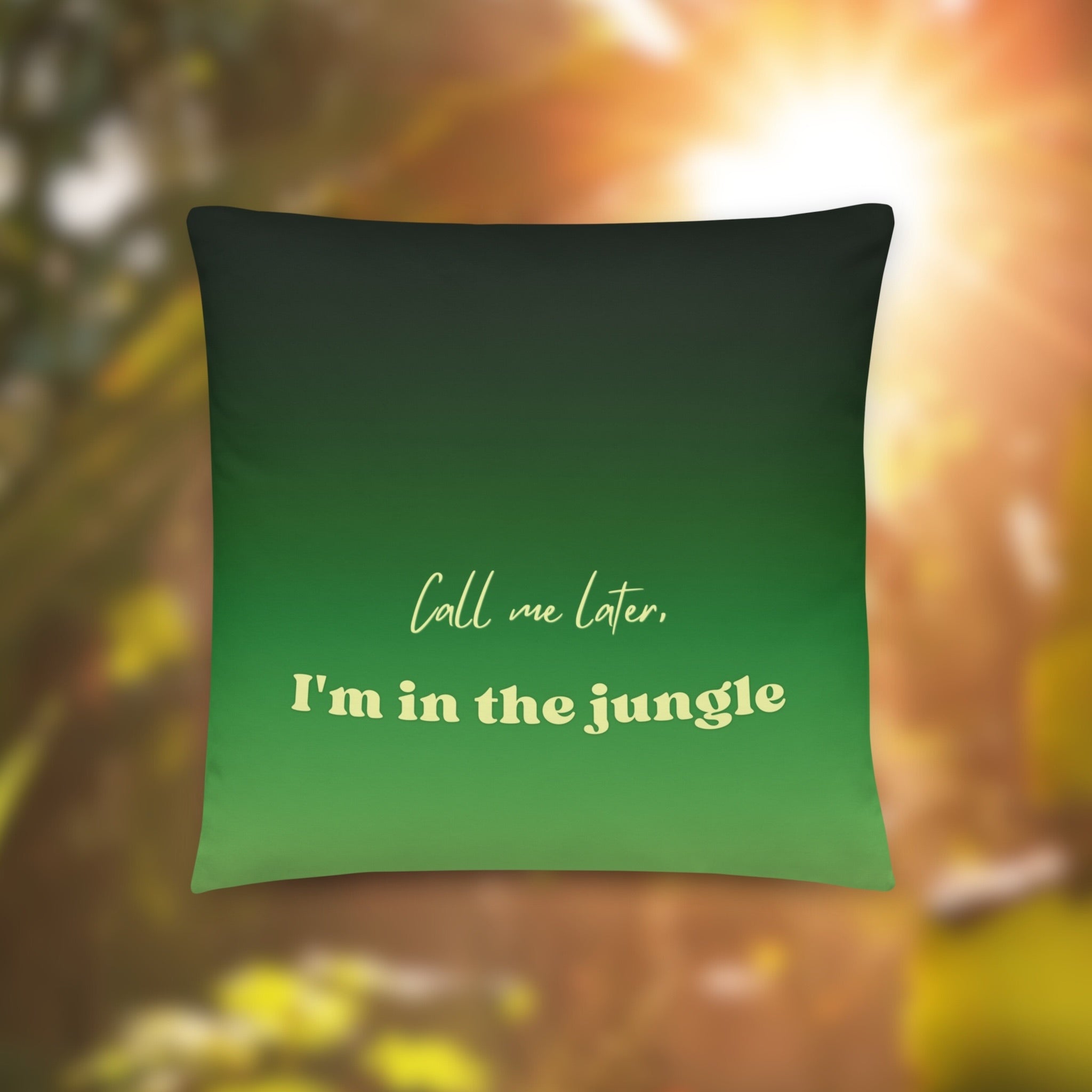 Green pillow with text 'Call me later, I'm in the jungle' on a blurred natural background