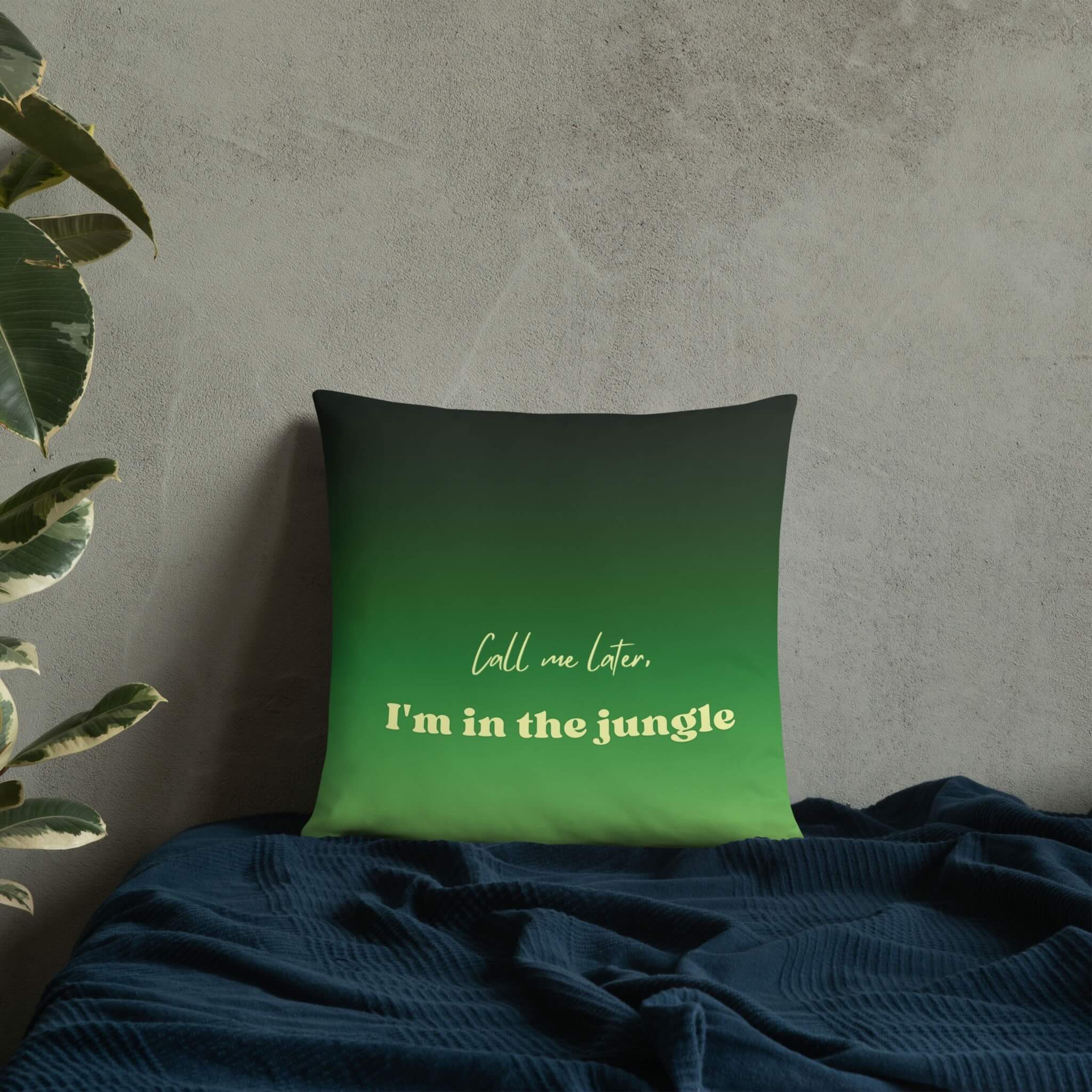 Green pillow with text 'Call me later, I'm in the jungle' on a textured wall background