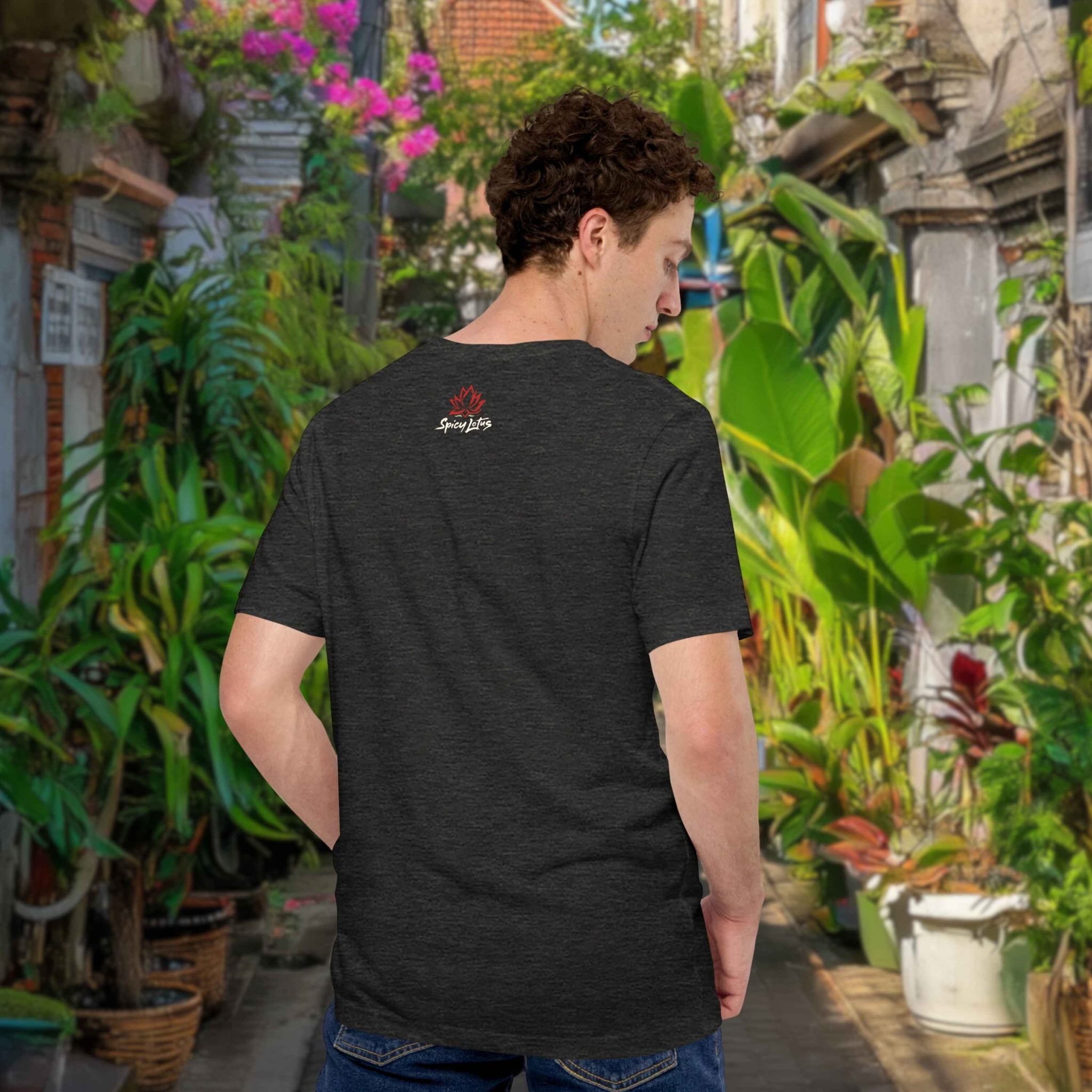 Person wearing a grey t-shirt with a logo in a street with plants