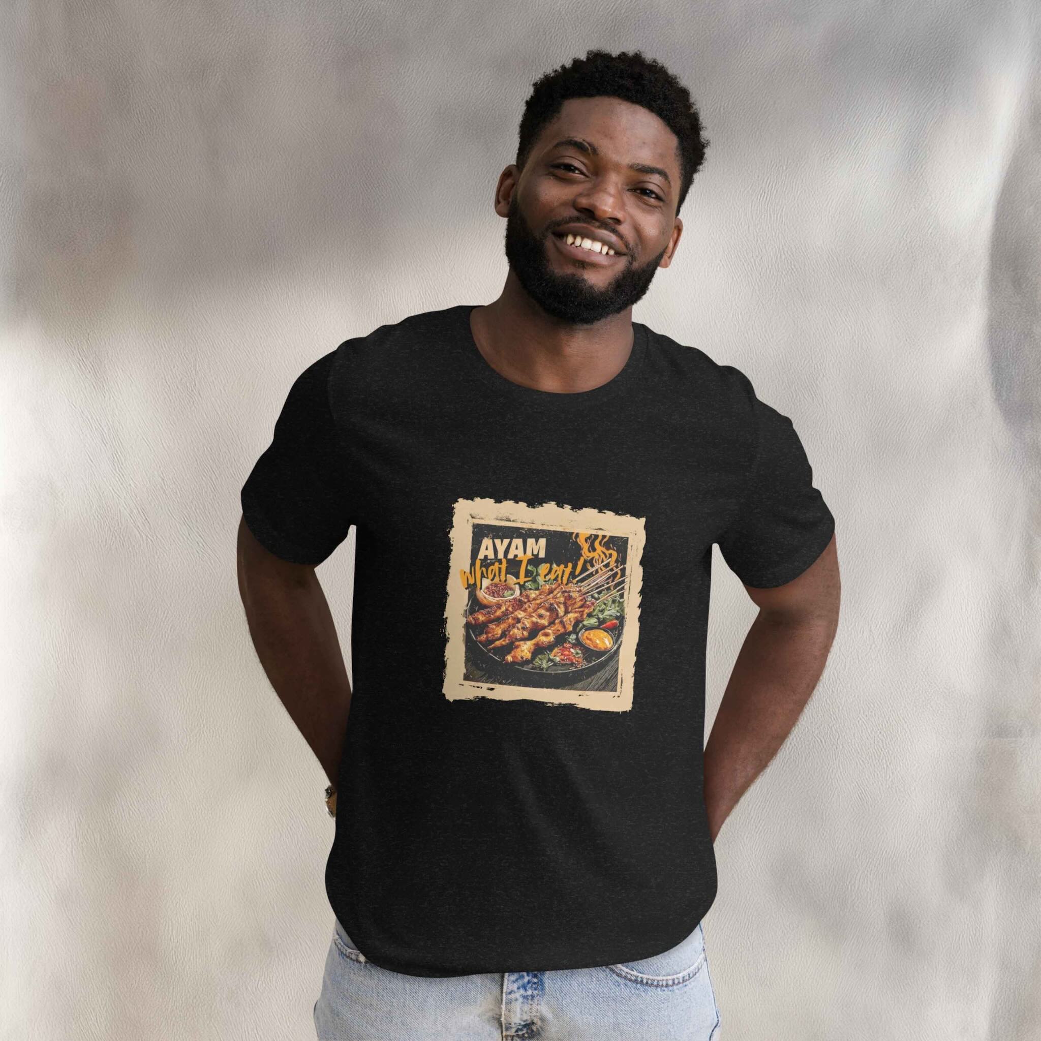Man wearing a black t-shirt with a graphic design of Ayam Sate on a neutral background