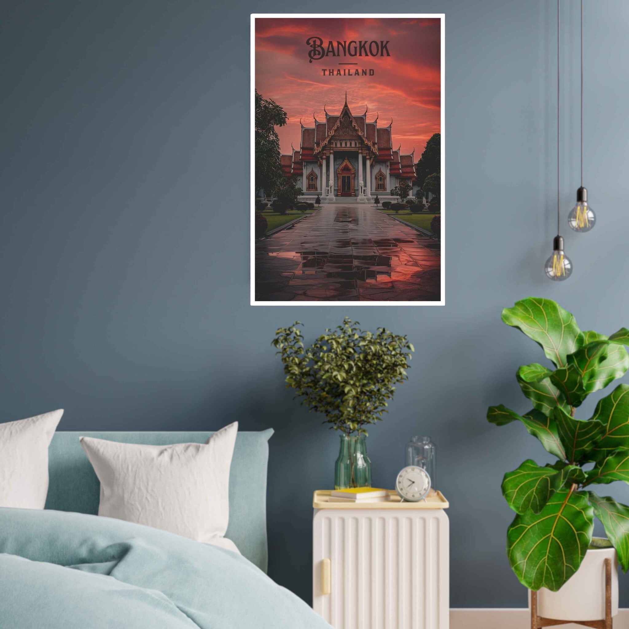 Poster of a temple in Bangkok on a wall above a bed with plants and a nightstand.