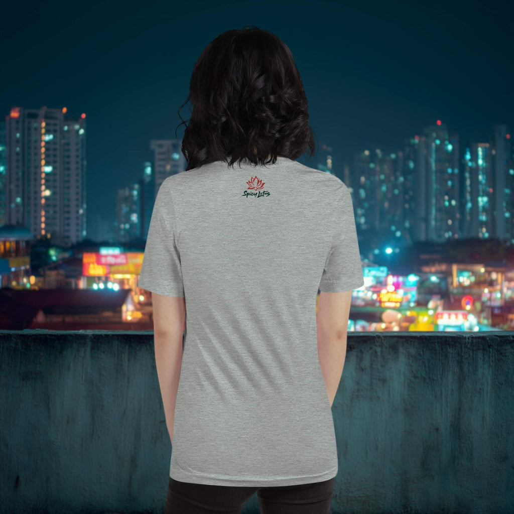Person wearing a gray t-shirt with a logo, standing against a city skyline at night.