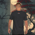 Man wearing a black t-shirt with a logo standing in front of a japanese stylized tree painting.