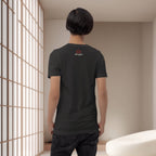 Person wearing a black t-shirt with a logo in a minimalistic room.