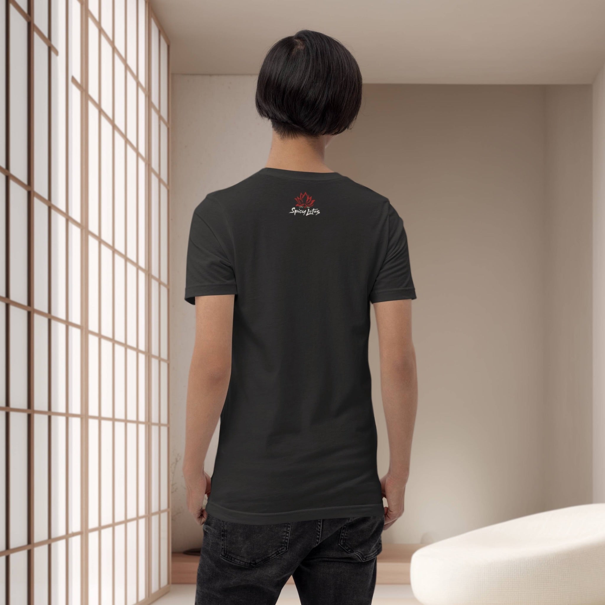 Person wearing a black t-shirt with a logo in a minimalistic room.