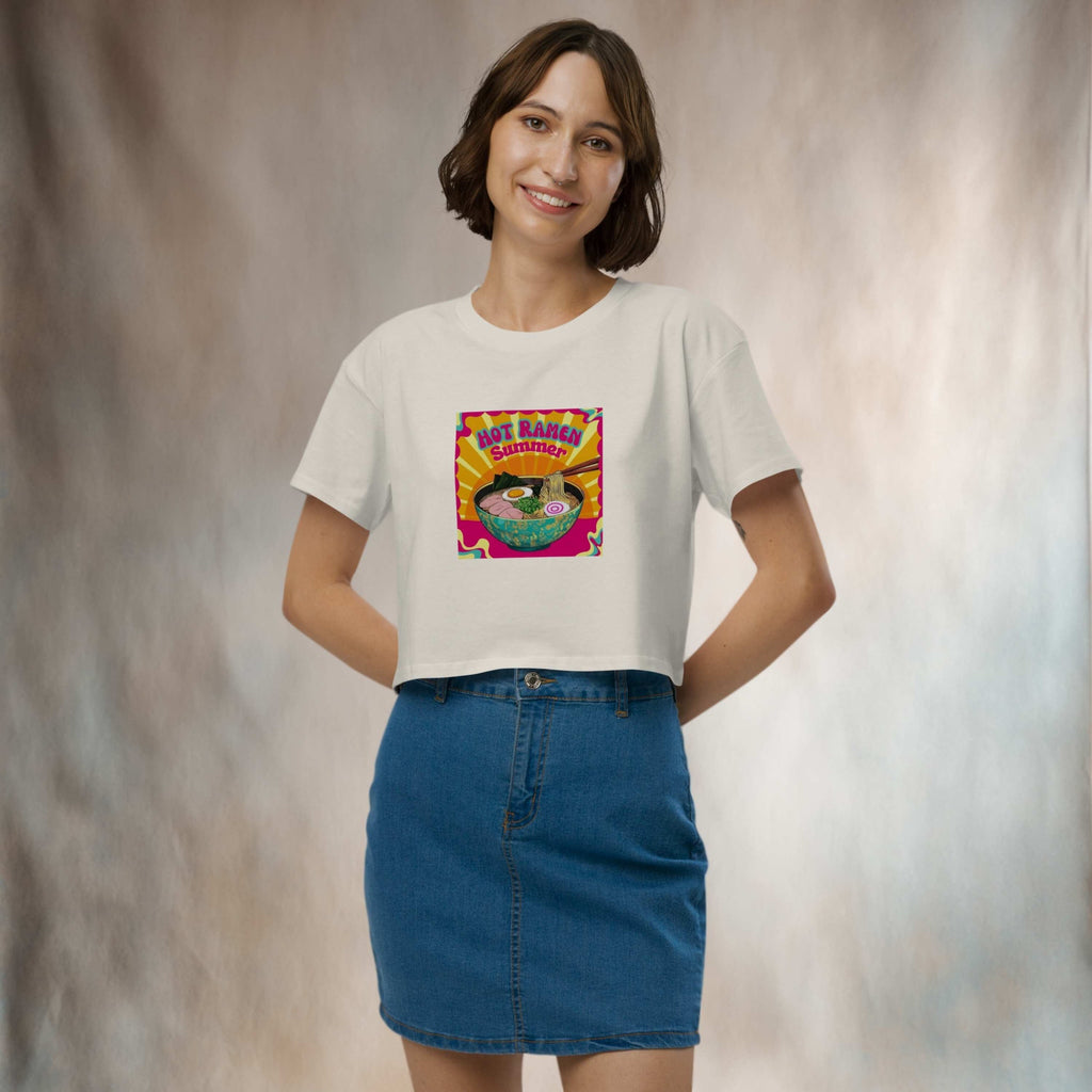 Woman wearing a white t-shirt with a colorful graphic design of 'Hot Ramen Summer' in front of a gray backdrop.