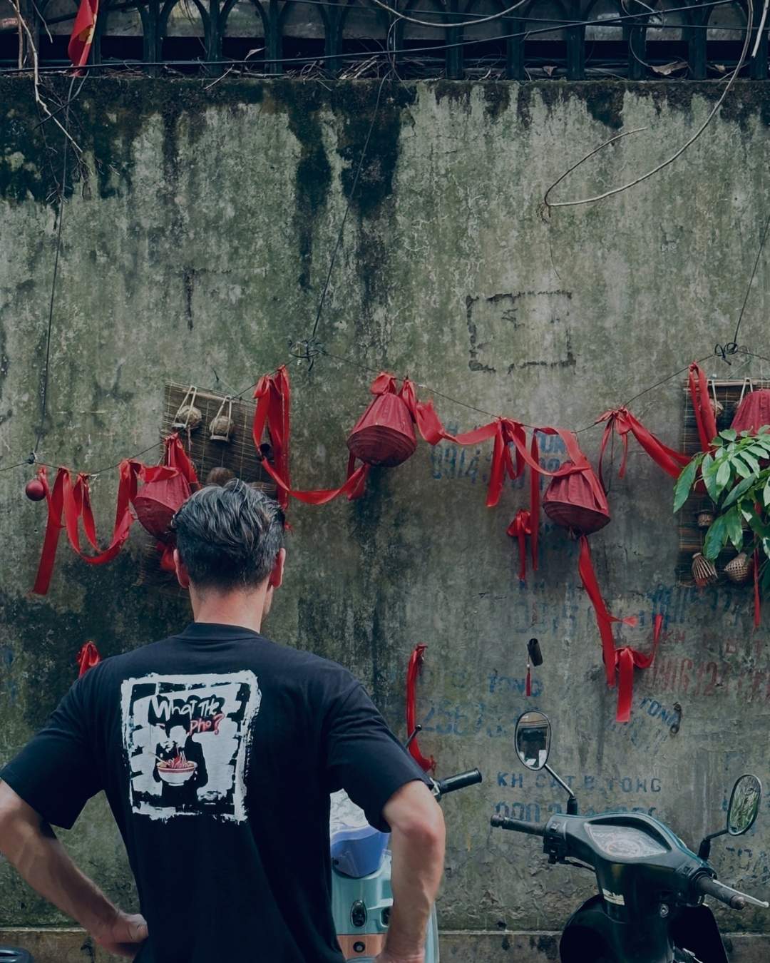 Person standing in a Vietnamese street wearing a Spicy Lotus shirt with graphic design.