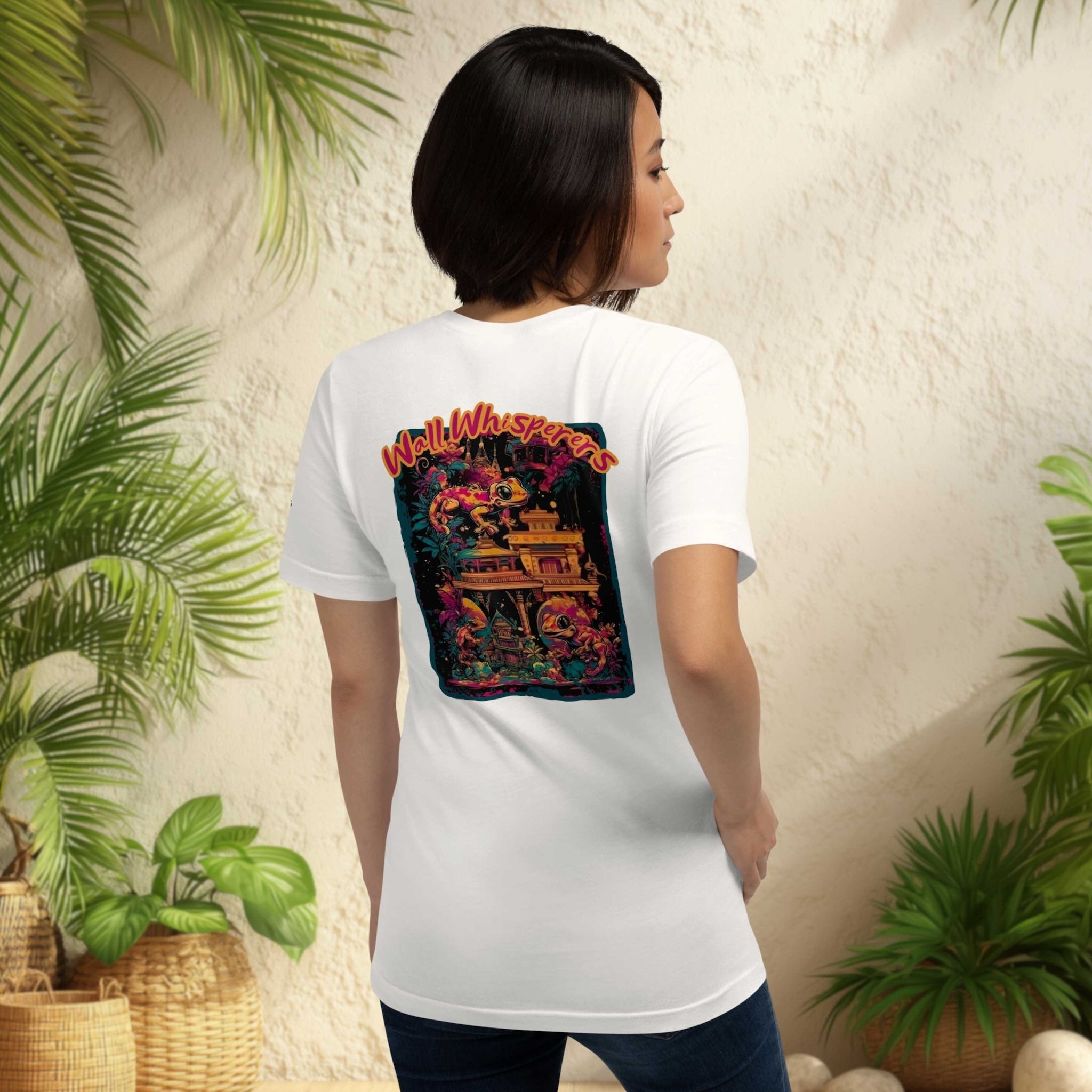 Wall Whisperers Midnight in Siam gecko back print white t-shirt on a woman standing in front of wall with tropical plants on both sides
