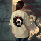 Person wearing a beige t-shirt with 'Grab Life by the Rice Ball' design, standing against an artistic background.