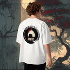 Person wearing a white t-shirt with a graphic design of japanese onigiri with pun on the back, standing against a stylized tree and wall background.