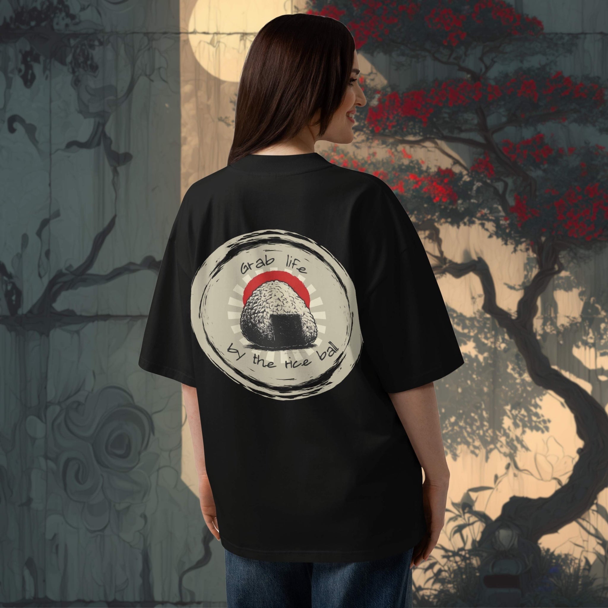 Person wearing an oversized black t-shirt with a graphic design in front of a japanese stylized tree background.