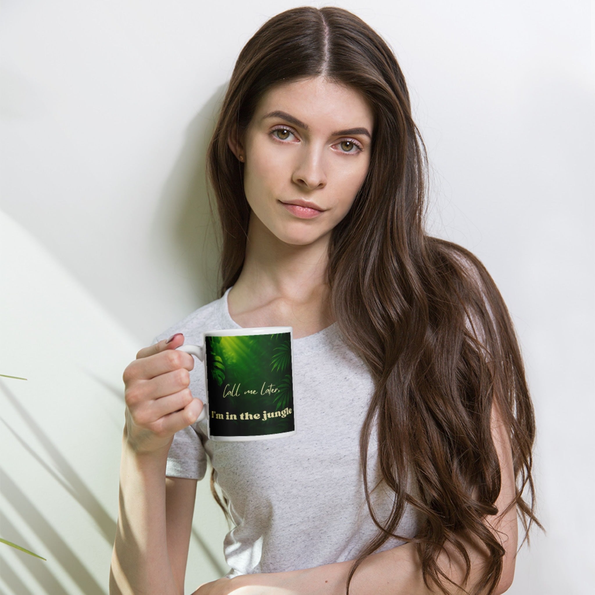 Woman holding a jungle design mug with a green design and text against a white background