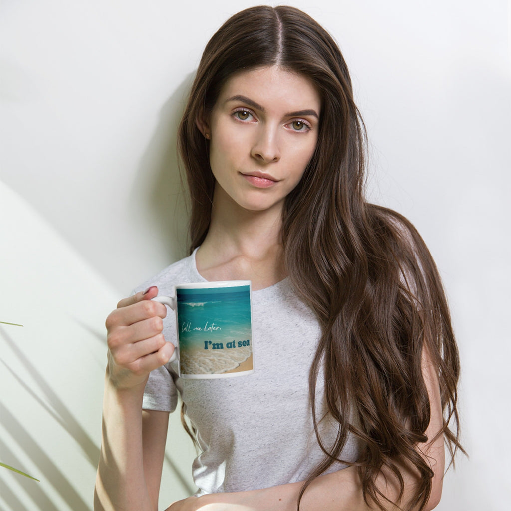 Woman holding a mug with a scenic design against a plain background