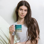 Woman holding a mug with a scenic design against a plain background