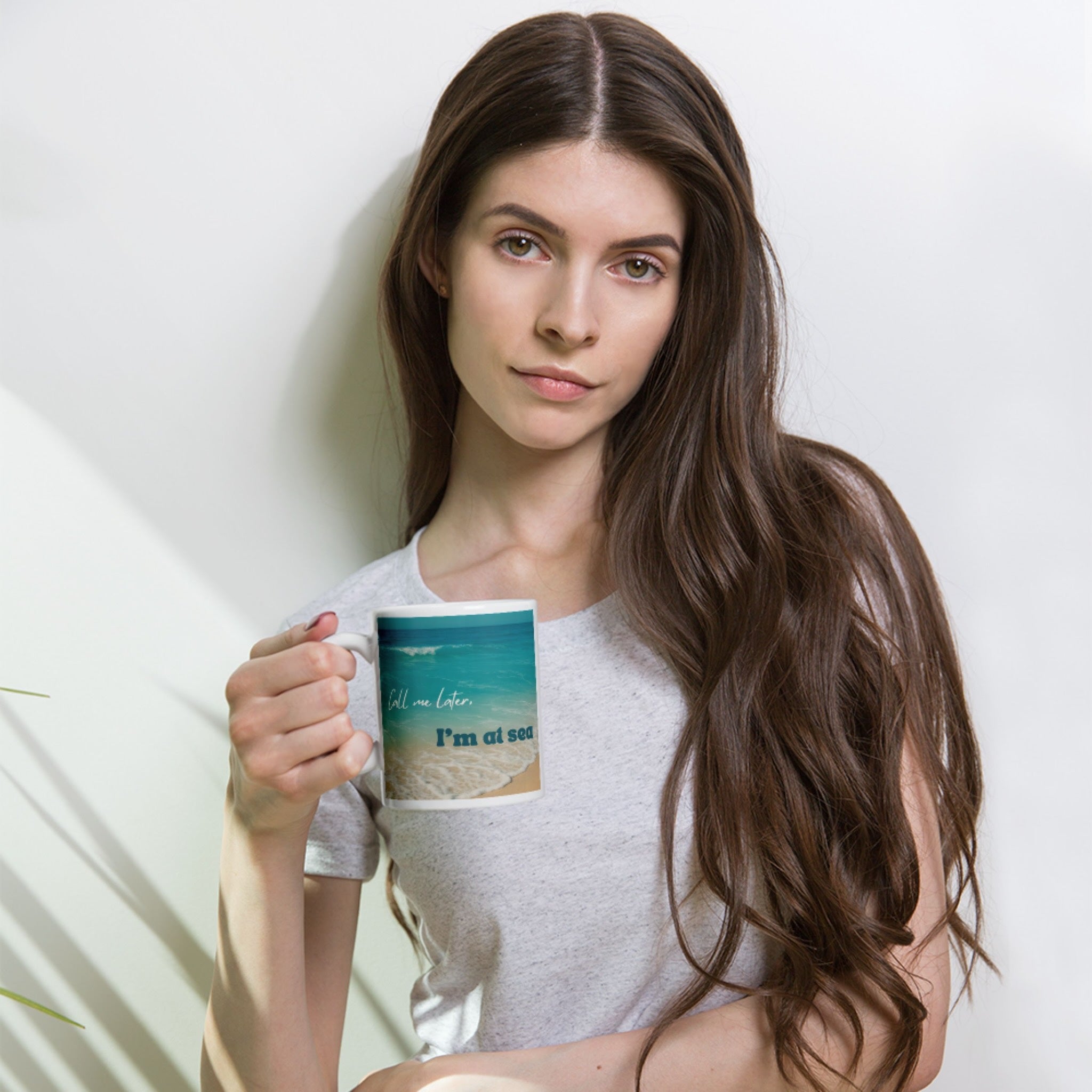 Woman holding a mug with a scenic design against a plain background