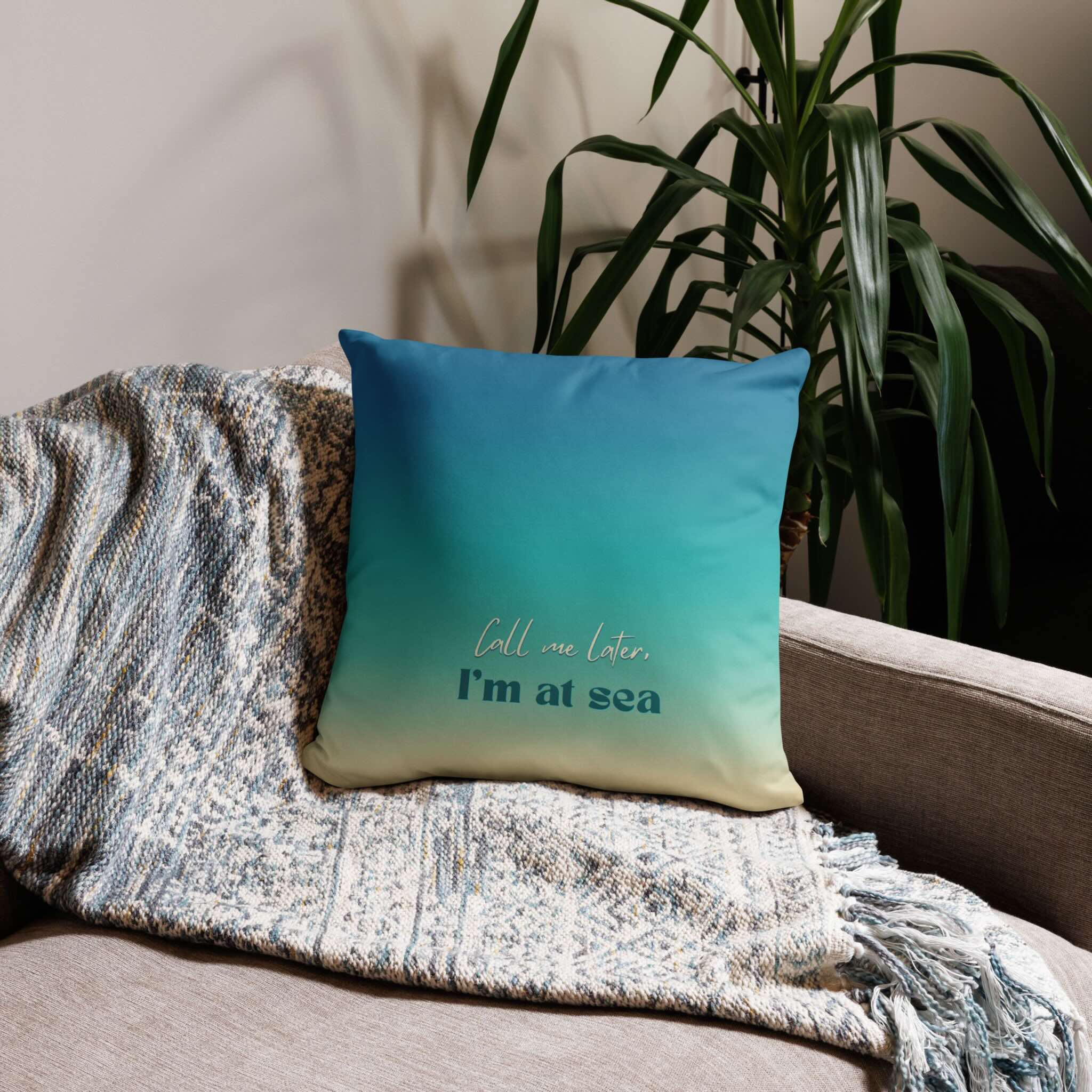 Blue pillow with text on a couch next to a plant