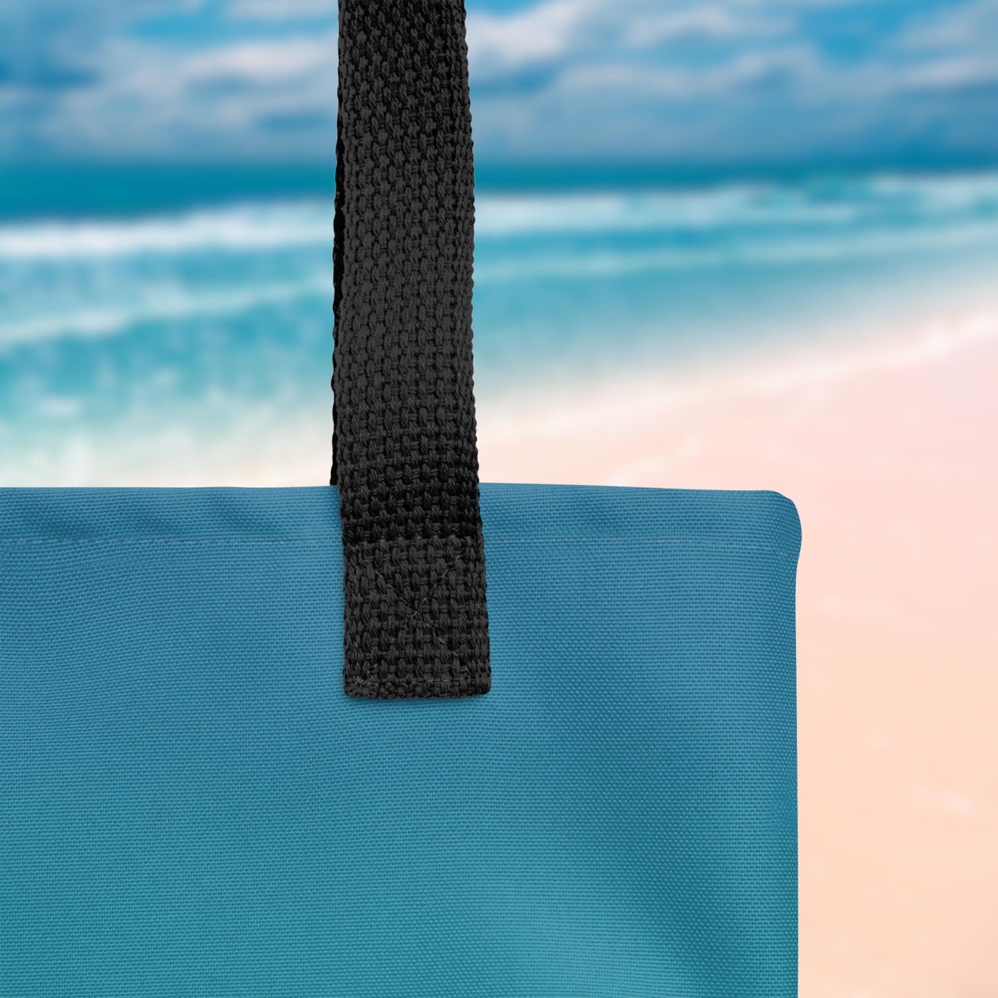 Close-up of a blue bag with a black strap against a beach background