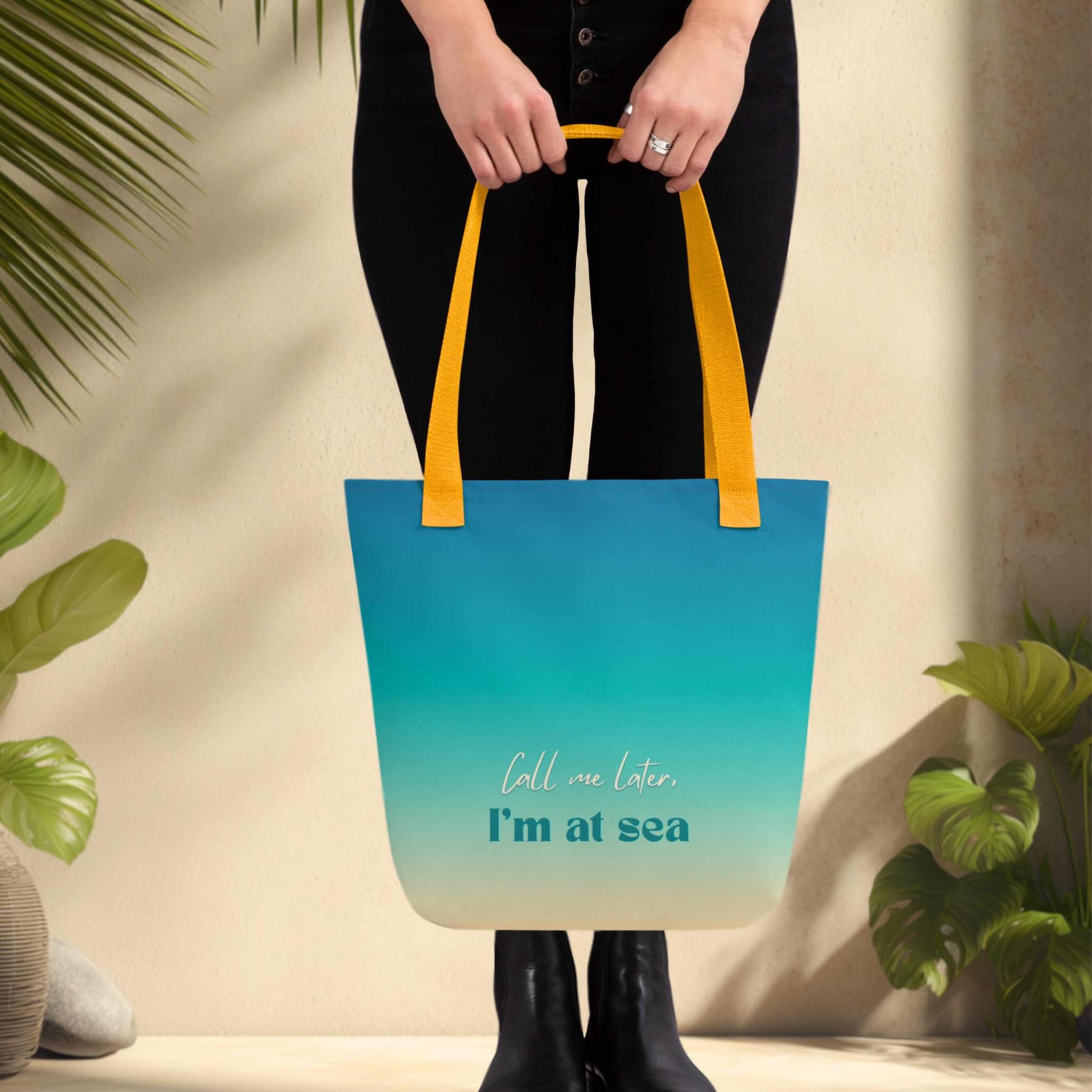 Woman holding a blue tote bag with yellow handles and text, surrounded by green plants.