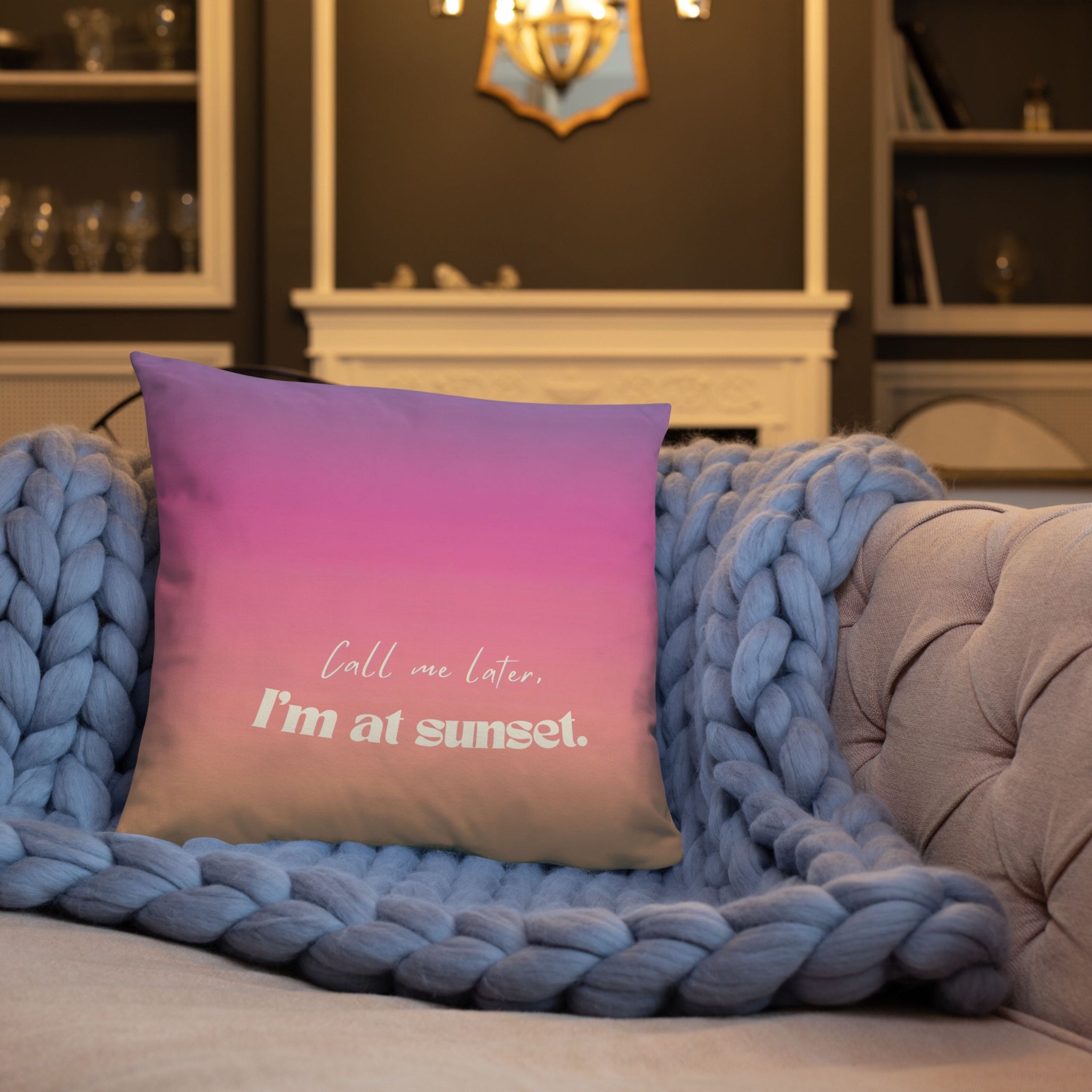 Decorative pillow with 'Call me later, I'm at sunset' text on a couch with a blue throw blanket.