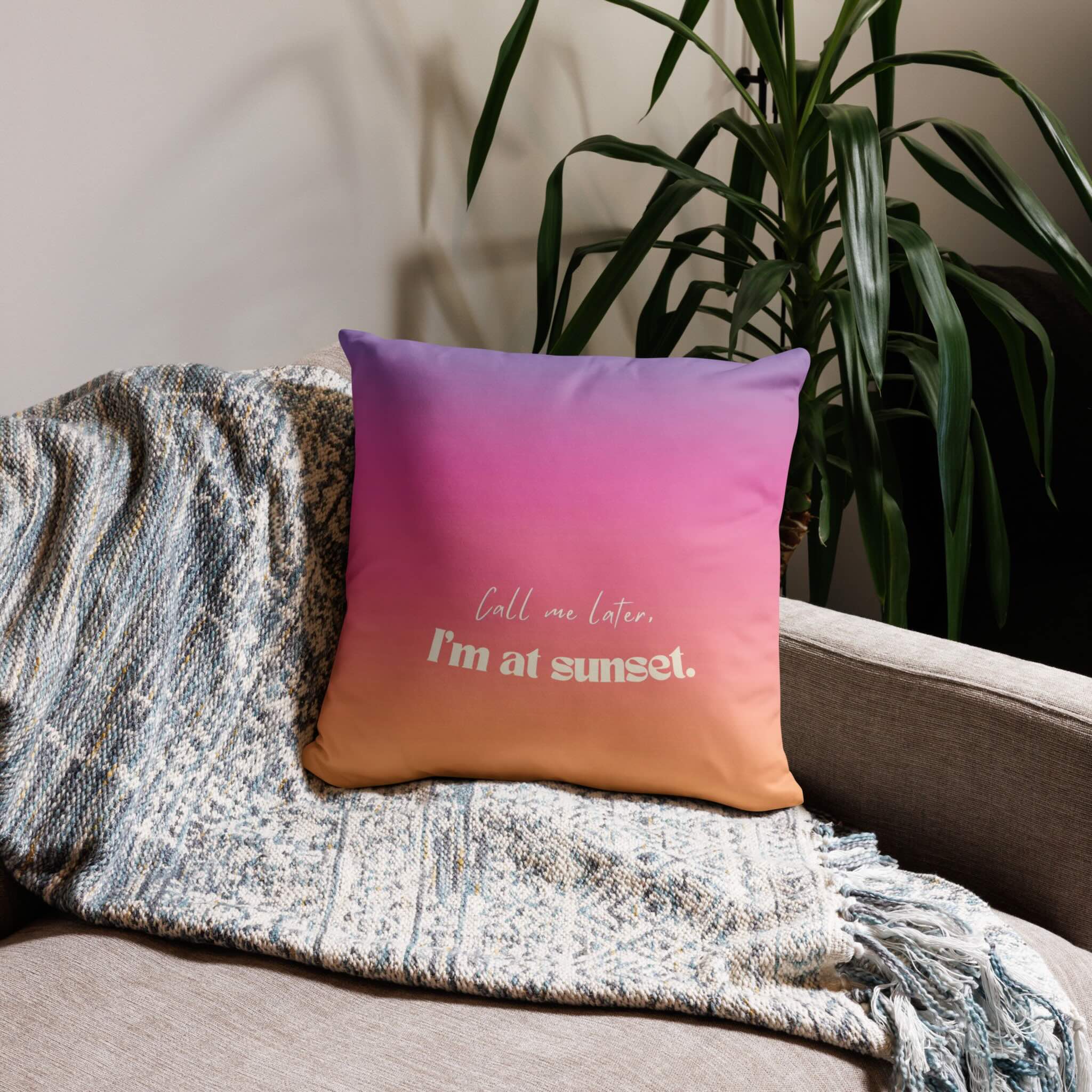Gradient pillow with text on a couch next to a plant