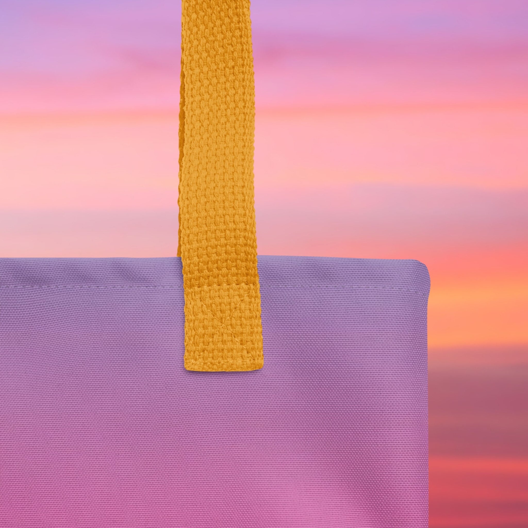 Close-up of a purple bag with a yellow strap against a colorful sunset background