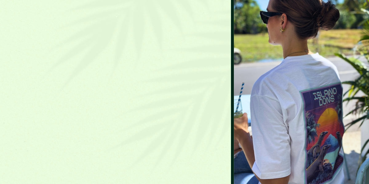 Person wearing a white Spicy Lotus t-shirt with a colorful graphic on the back, sitting outdoors.