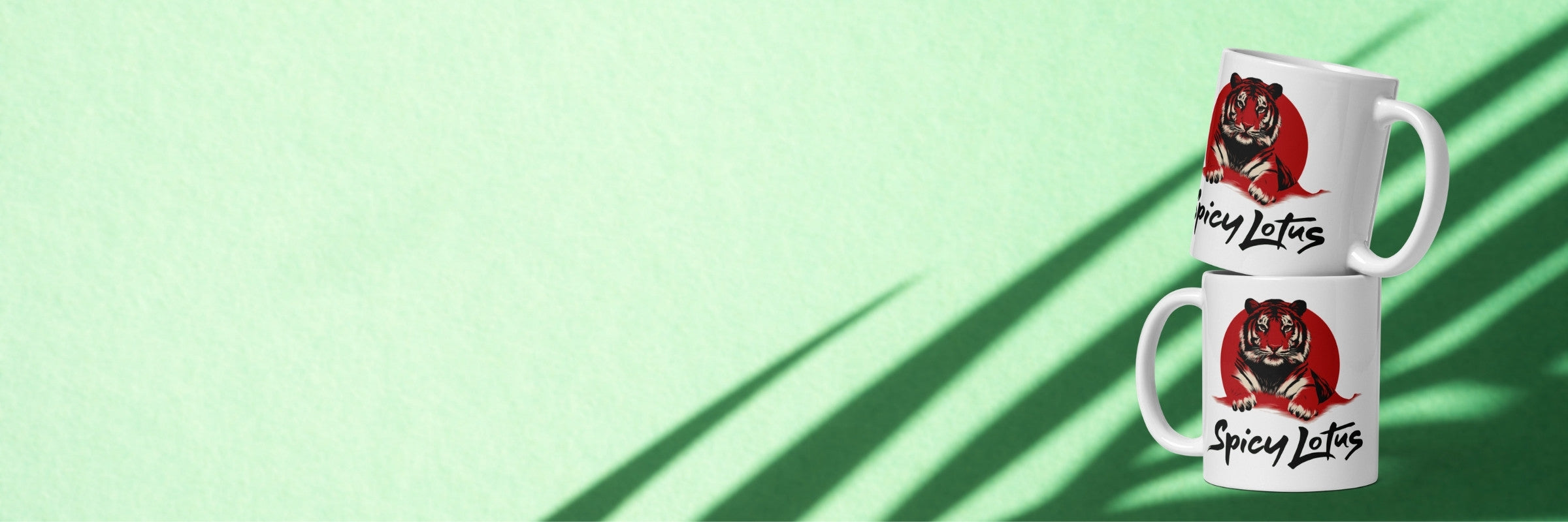 Two white mugs with a red and black design on a light green background with tropical shadows