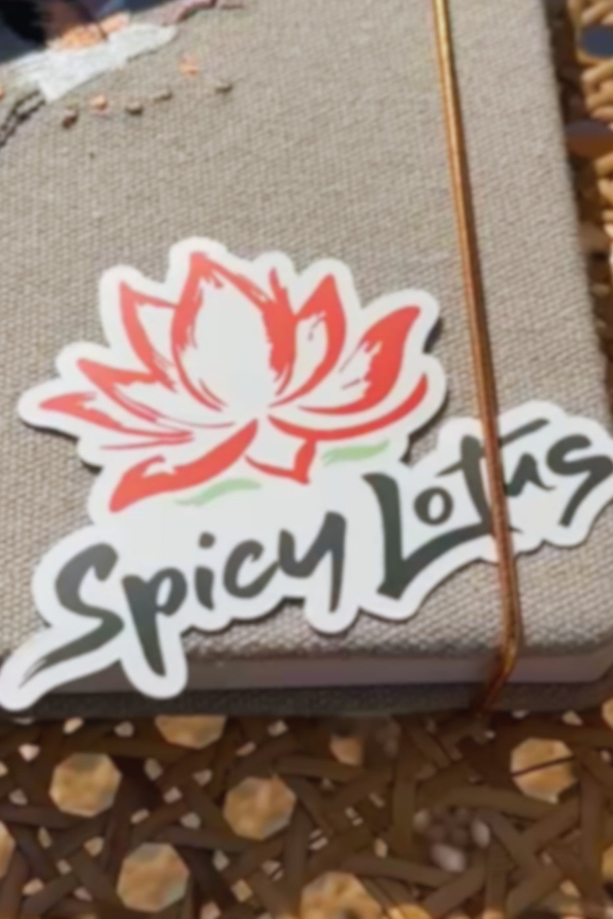 Spicy Lotus logo on a product packaging with a woven book cover background