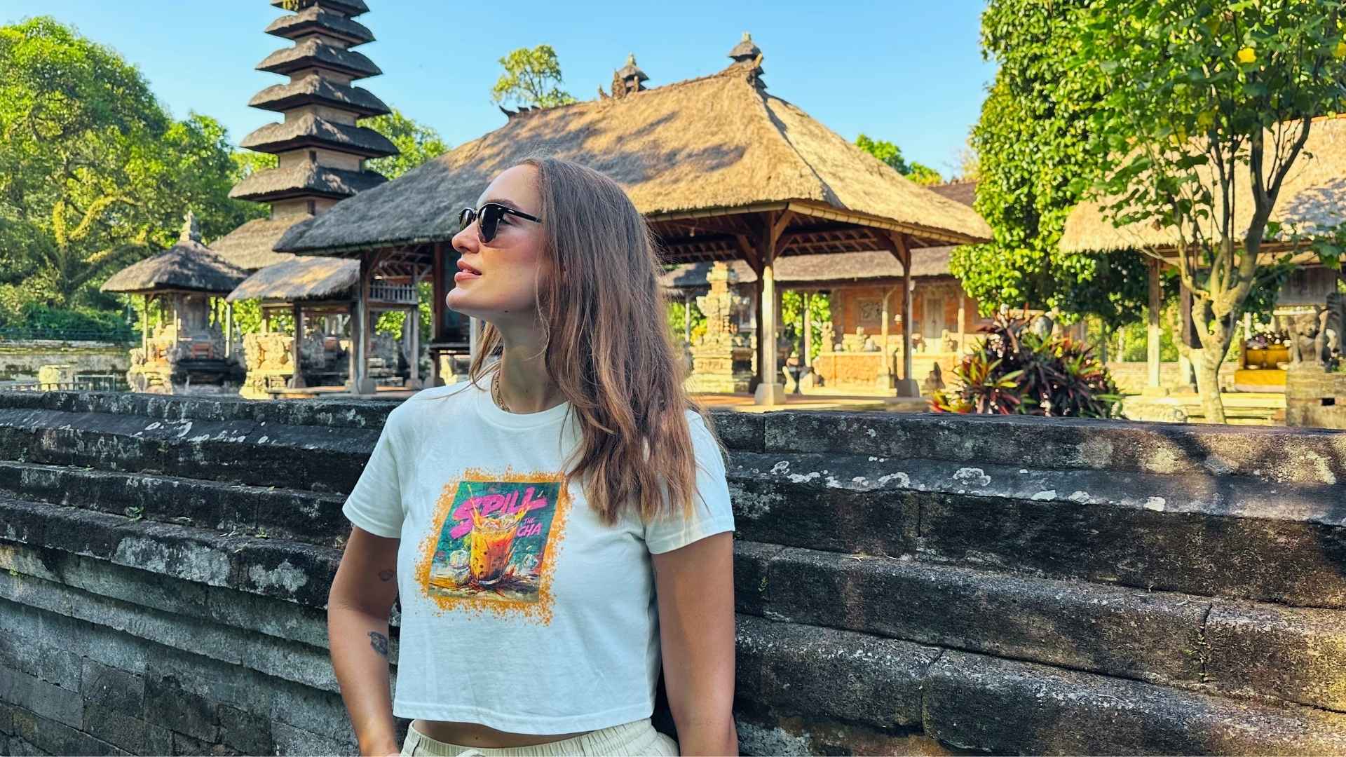 Woman standing in front of traditional Balinese architecture with a temple in the background.