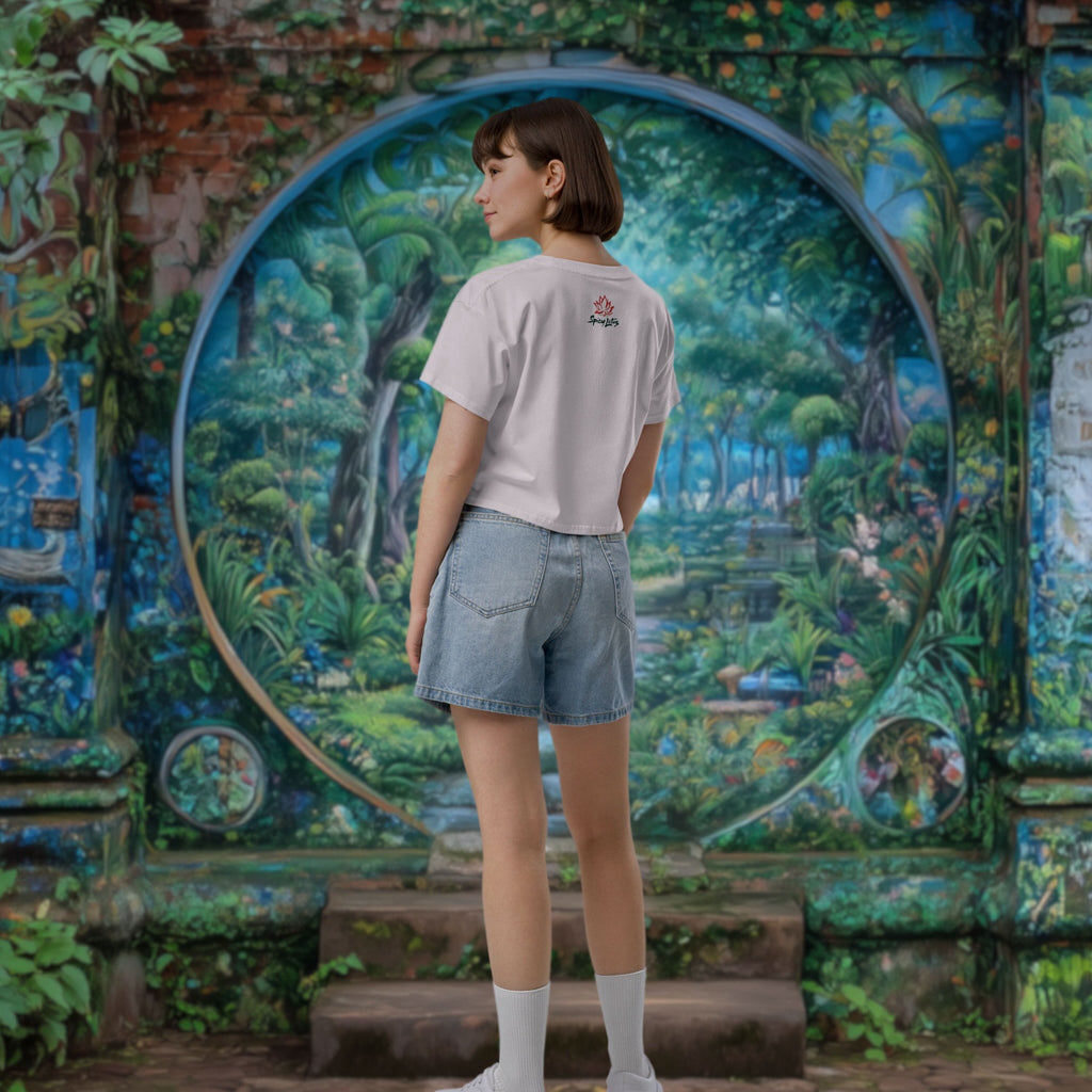 Woman standing in front of a colorful mural with a garden scene, wearing a t-shirt with a logo on the back