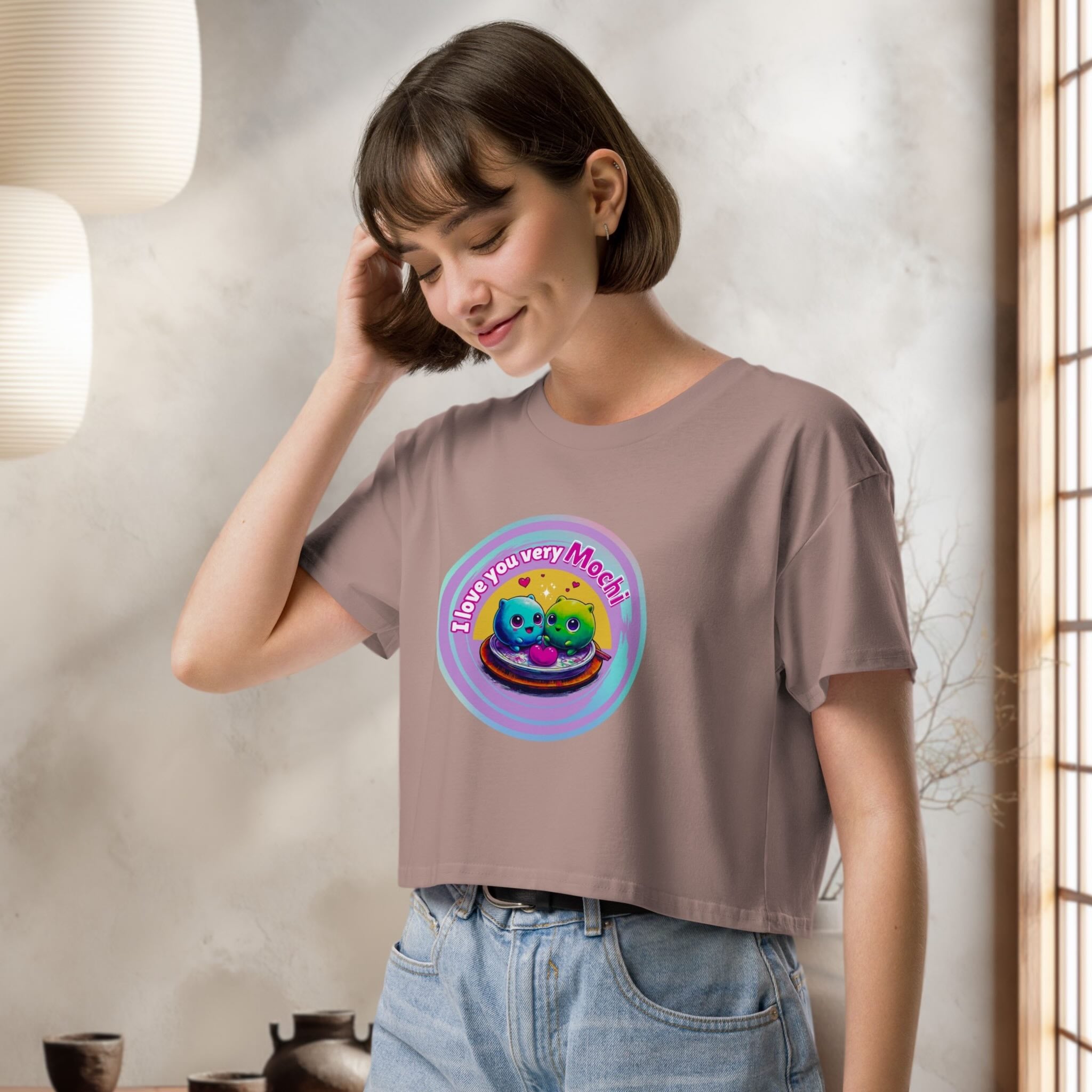 Woman wearing a brown t-shirt with a colorful graphic design of cute japanese mochis indoors.
