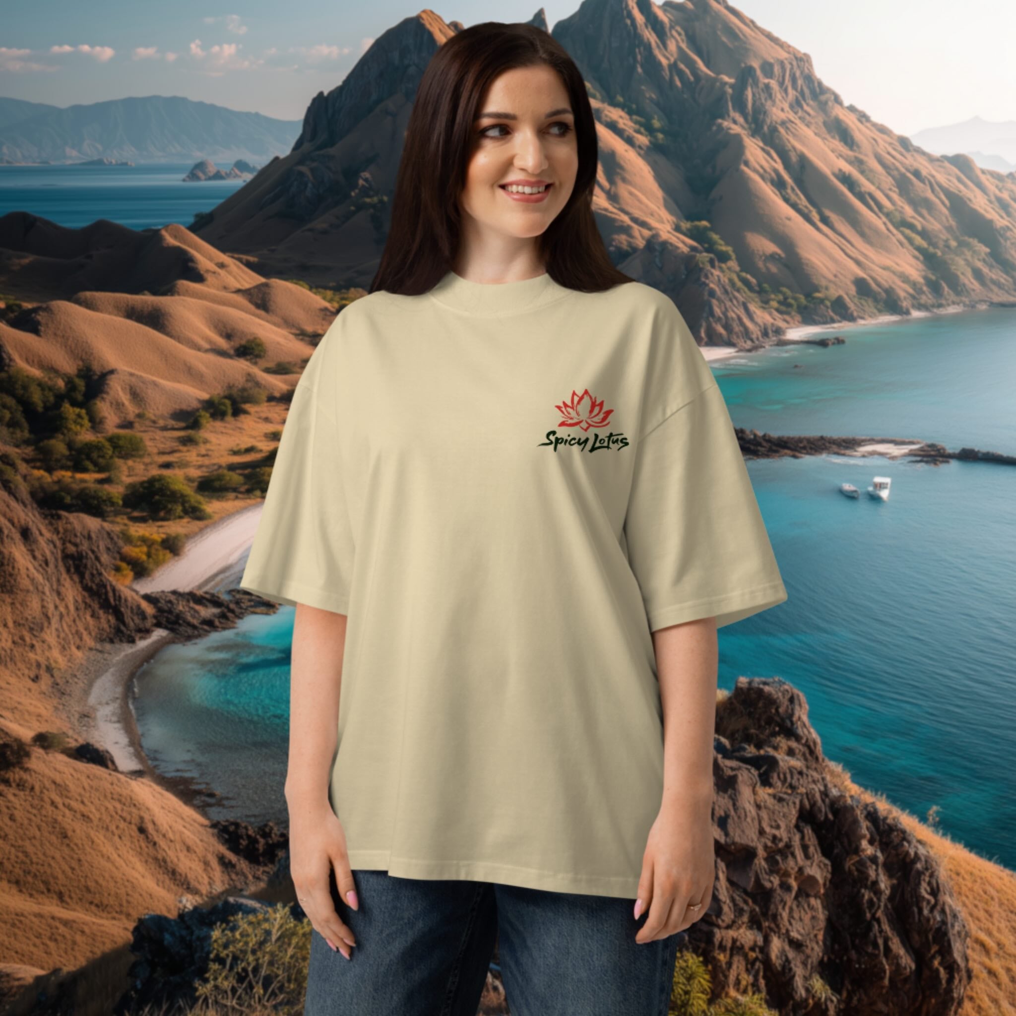 Woman wearing a beige oversized organic t-shirt with a lotus flower logo in front of a scenic mountain and ocean backdrop at Komodo Island viewpoint, Indonesia.