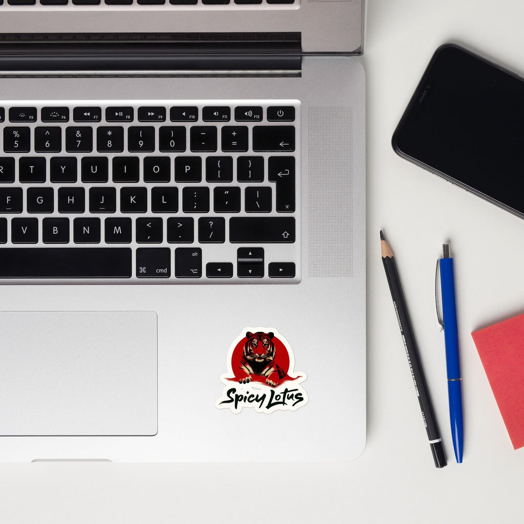 Laptop with a Tiger sticker, phone, and writing utensils on a white surface