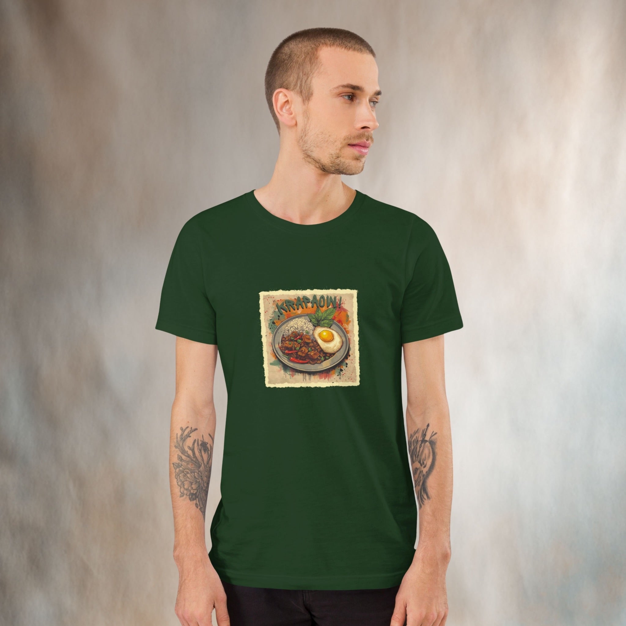 Man wearing a green t-shirt with a graphic design of 'Krapaow' Thai street food Pad Kra Pao graphic on a textured background