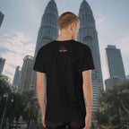 Person wearing a black t-shirt with a logo in front of the Petronas Twin Towers.
