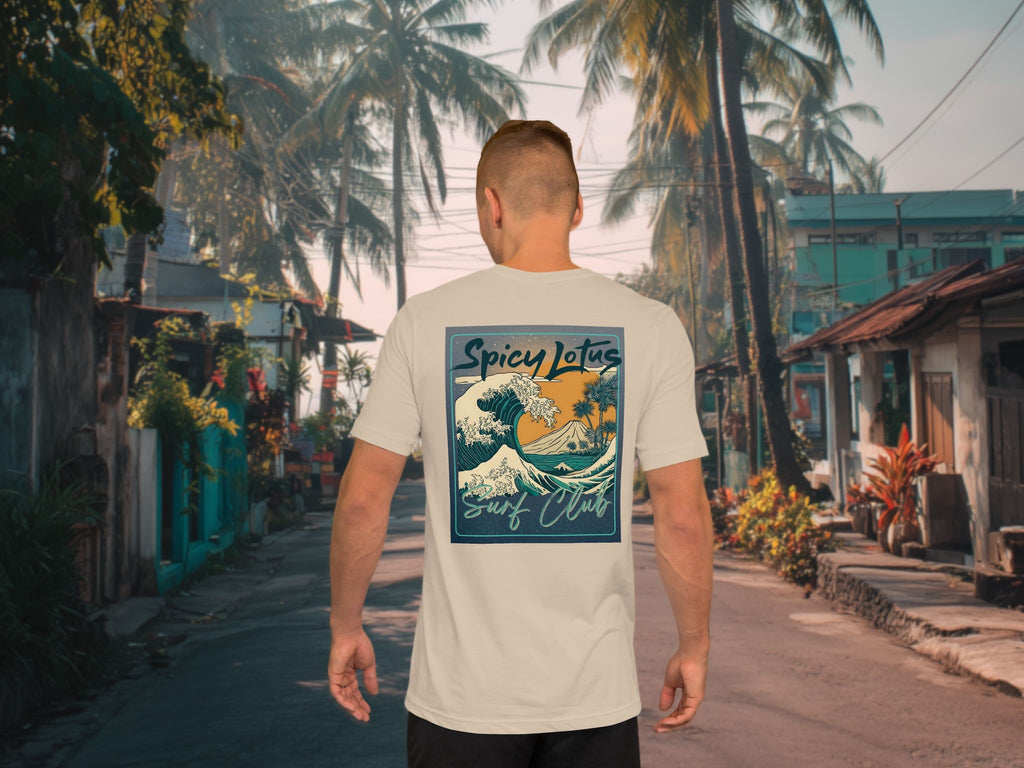 Man walking on a street with palm trees wearing a t-shirt with a 'Spicy Lotus Surf Club' design.