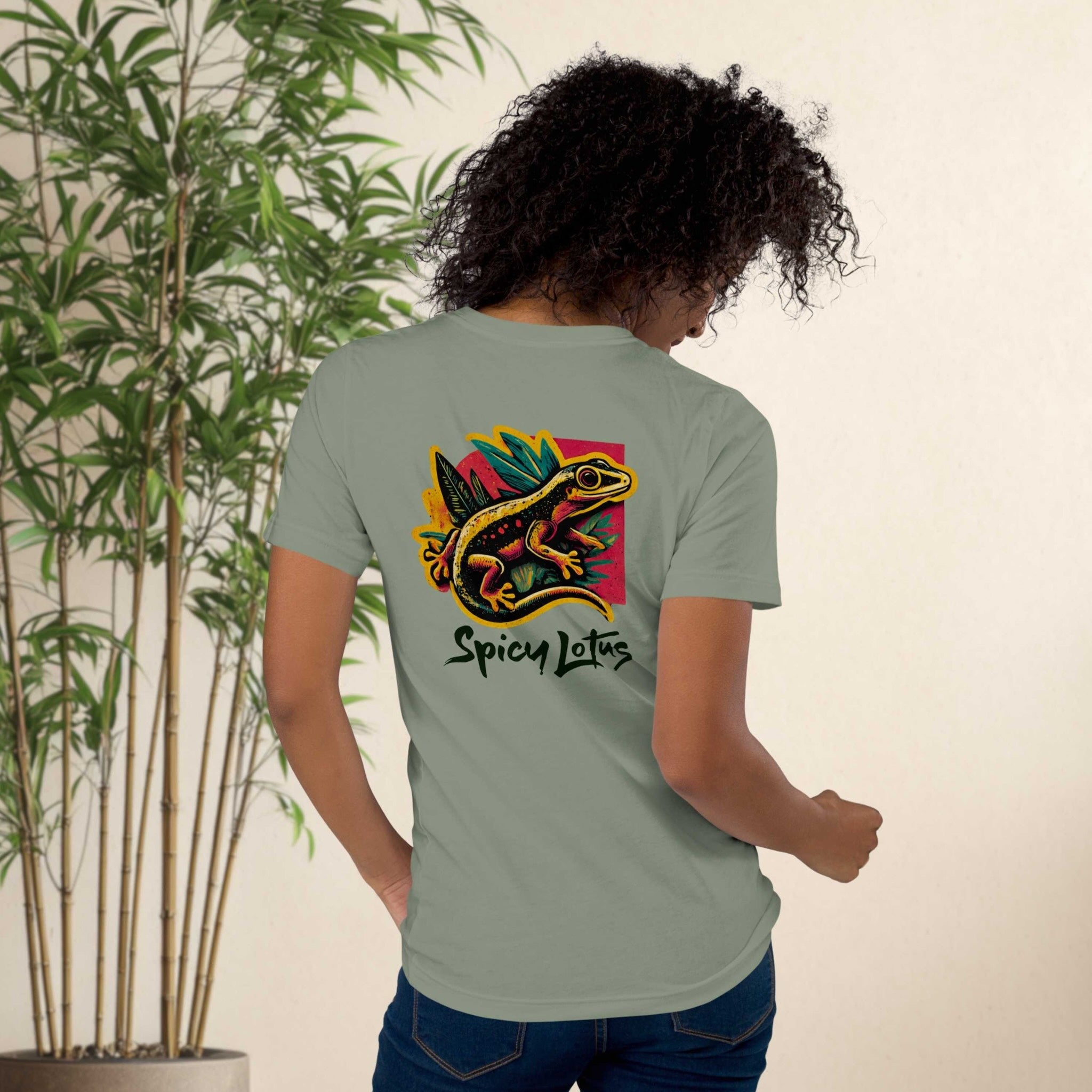 Person wearing a green t-shirt with a colorful lizard design and 'Spicy Lotus' text, standing in front of a plant.