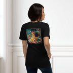 Person wearing a black t-shirt with a colorful graphic of a mie noodle dish on the back, standing against a white wall.