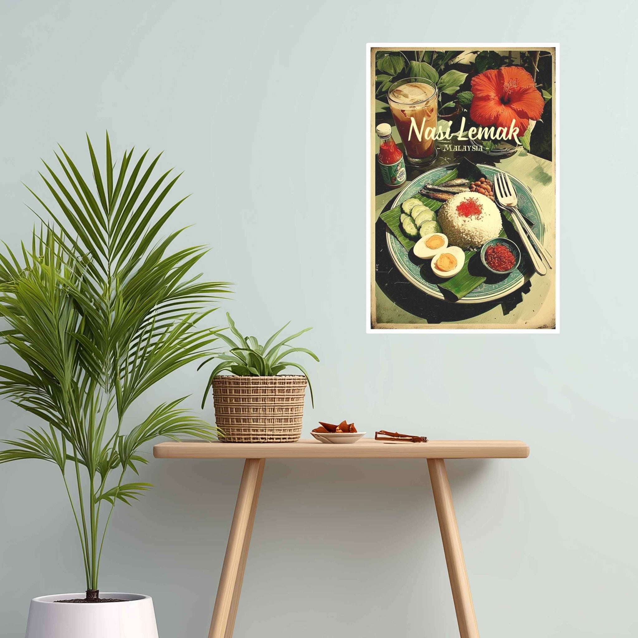 Poster of Nasi Lemak on a wall above a wooden table with plants.