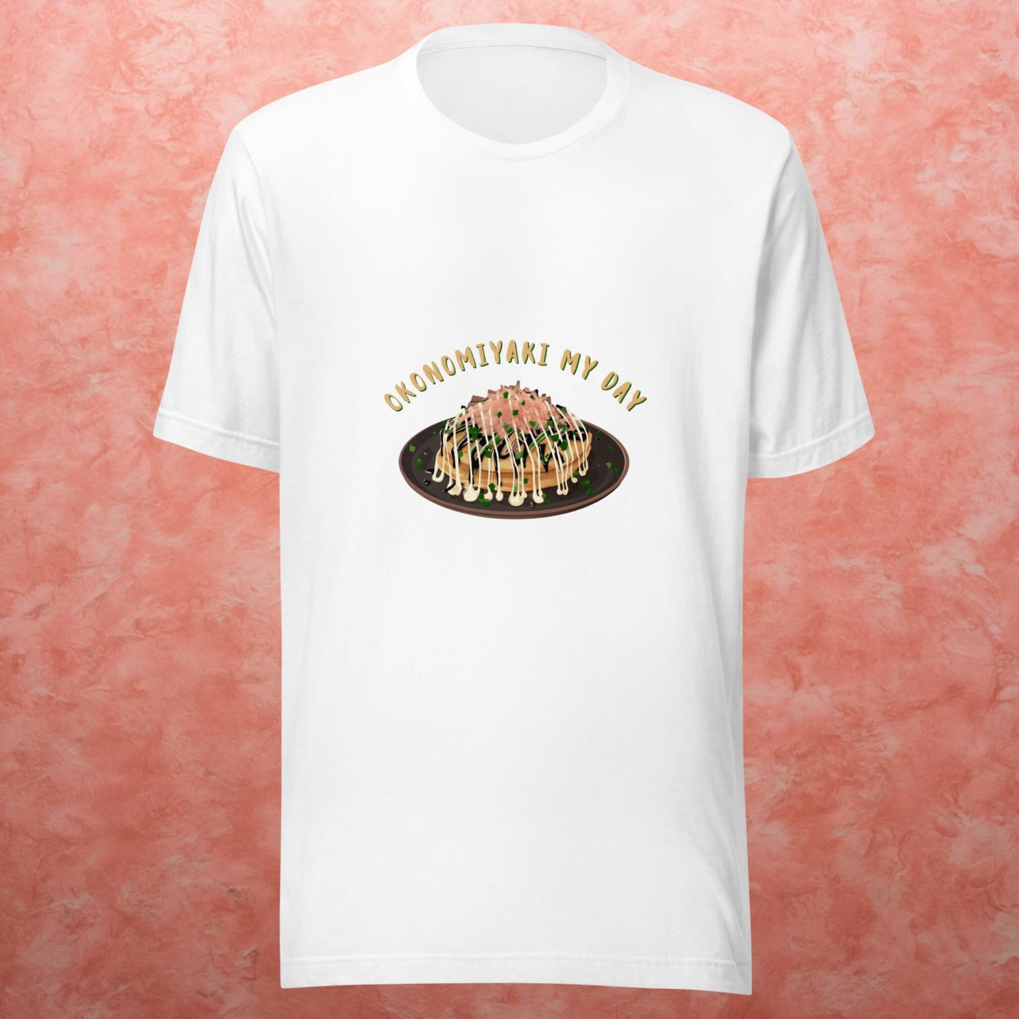 White t-shirt with an okonomiyaki graphic design on a pink textured background